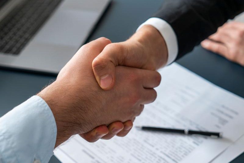 Stretta di mano sopra un contratto firmato